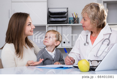 Pediatrist woman is examining kid and talking to his mother about it 66401081