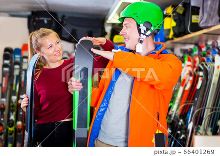 Saleswoman is helping man in ski equipment 66401269