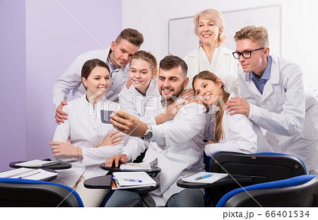 Positive medical students and woman professor taking selfie Positive medical students and woman professor taking selfie 66401534