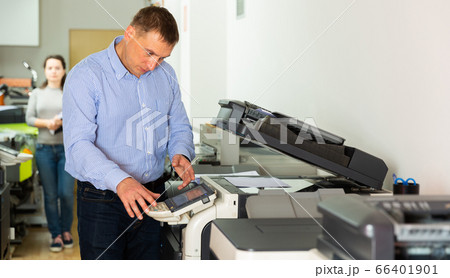 Confident businessman using printer in office Confident businessman using printer in office 66401901