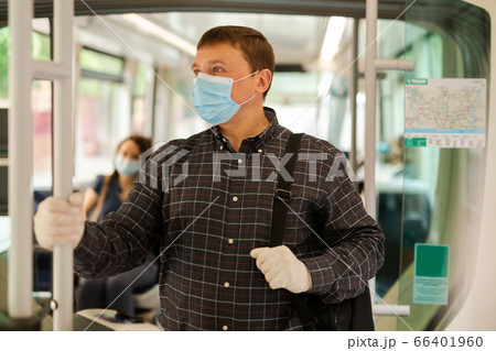 Passenger in disposable mask in city streetcar 66401960