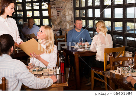 Waitress showing menu card to couple 66401994