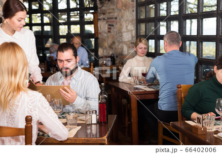 Waitress showing menu card to couple 66402006