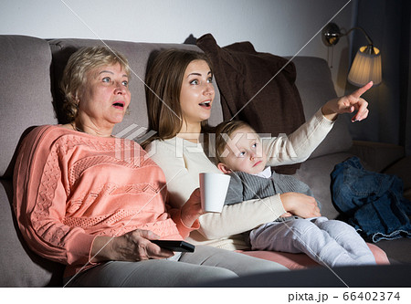 Two women and toddler are enjoying of watch film in evening 66402374