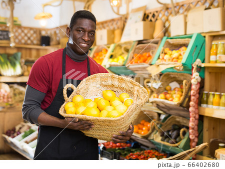 Greengrocery owner offering citrus fruits Greengrocery owner offering citrus fruits 66402680