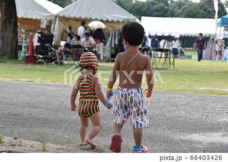 水着でフリーマーケットを散歩する男の子の兄弟の後ろ姿の写真素材