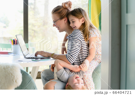 Children (4-5, 6-7) climbing on their mother while she works from home Children (4-5, 6-7) climbing on their mother while she works from home 66404721