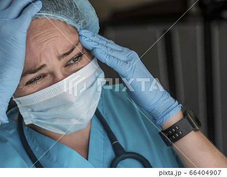 Nurse in face mask experiencing symptoms Nurse in face mask experiencing symptoms 66404907