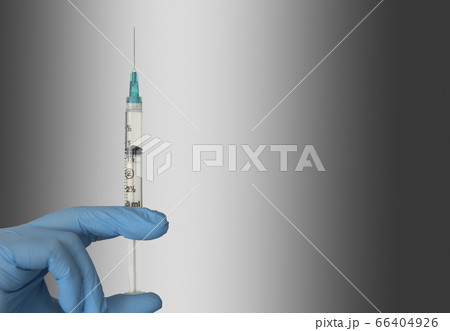 Close-up of hand in blue surgical glove holding syringe Close-up of hand in blue surgical glove holding syringe 66404926