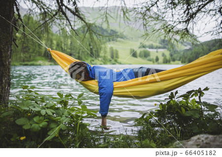 Switzerland, Bravuogn, Palpuognasee, Young woman resting in hammock near Palpuognasee lake in Swiss Alps 66405182