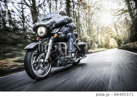 United Kingdom, London, Motorcyclist on road in forest 66405371