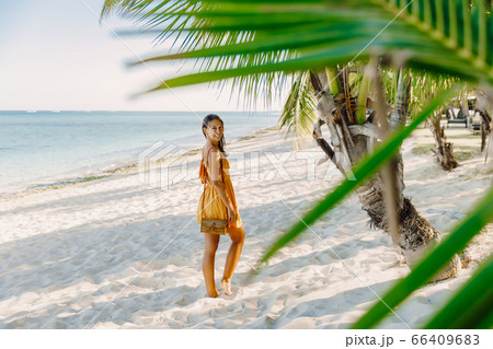Young woman in dress at tropical palm beach. Tropical vacations in paradise Young woman in dress at tropical palm beach. Tropical vacations in paradise 66409683