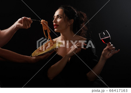 Beautiful girl eats spaghetti and drinks wine Beautiful girl eats spaghetti and drinks wine 66417163