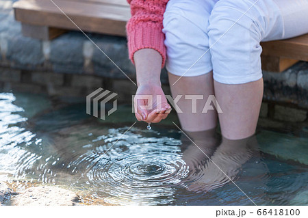 女子旅で足湯のお湯を掬う女性 1月 撮影協力 鬼石坊主地獄 の写真素材