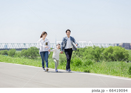 土手を手を繋いで歩く家族 66419094
