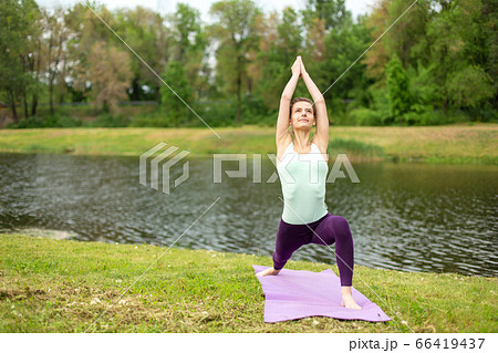 A young sports girl practices yoga on a green lawn A young sports girl practices yoga on a green lawn 66419437
