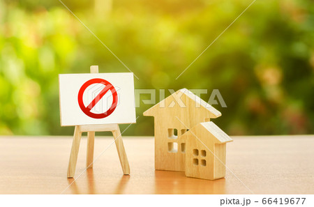 Wooden houses and an easel with a red prohibition sign NO. Inaccessibility and lack of housing, deficit. Seizure and freezing of assets by a bank, court. Illegal buildings, demolition elimination 66419677