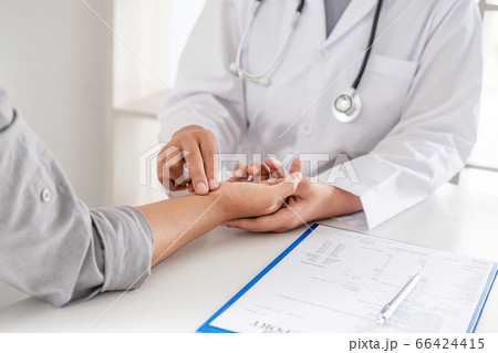 The doctor examines the patient's pulse by hand and records the results 66424415