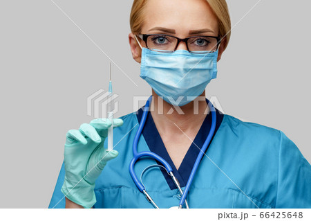 medical doctor nurse woman wearing protective mask and gloves - holding syringe medical doctor nurse woman wearing protective mask and gloves - holding syringe 66425648