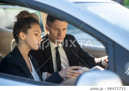 Serious man and woman with documents in a car Serious man and woman with documents in a car 66425733