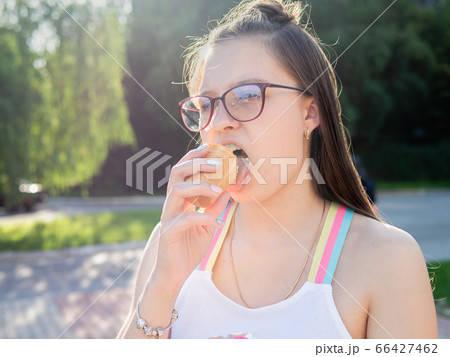 Portrait of teenager girl in summer in the sun with the appetite and pleasure of eating ice cream. Portrait of teenager girl in summer in the sun with the appetite and pleasure of eating ice cream. 66427462