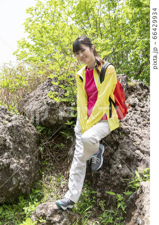 緑に囲まれた森の中の大きな岩で座ってポーズをとる女性 66429934
