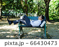 Asian businessman is lying on bench. 66430473