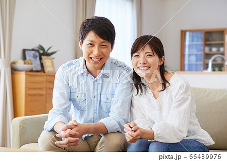 リビングのソファーに座るカップルの写真素材