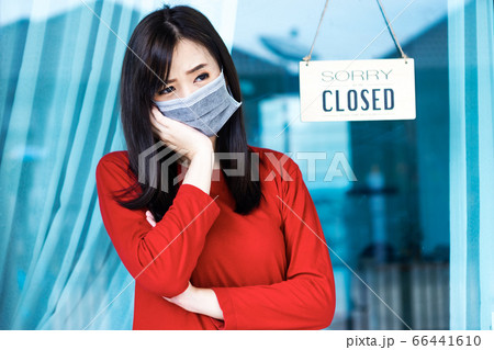 Asian woman shop owner hanging label 'Sorry we are 66441610