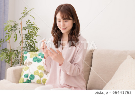 ソファーに座ってスマホを見る若い女性 66441762