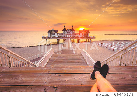 Young man sitting on wooden pier enjoying sunrise Young man sitting on wooden pier enjoying sunrise 66445173