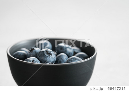 Ripe blueberries in black bowl on concrete background with copy space 66447215