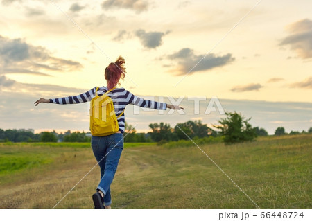 Young girl with yellow backpack, her back with open hands 66448724