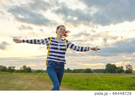 Running young girl with yellow backpack, with open hands 66448726