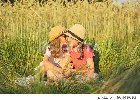 Two smiling girls sitting in grass, children talking 66449693