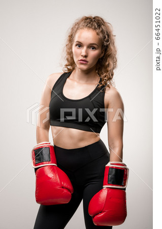 Blond girl in black tracksuit and red boxing gloves standing in front of camera Blond girl in black tracksuit and red boxing gloves standing in front of camera 66451022