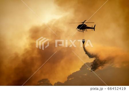 Helicopter dumping water on forest fire 66452419