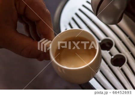 Close up view of the hand of a man working in a coffee house preparing espresso coffee waiting for 66452693