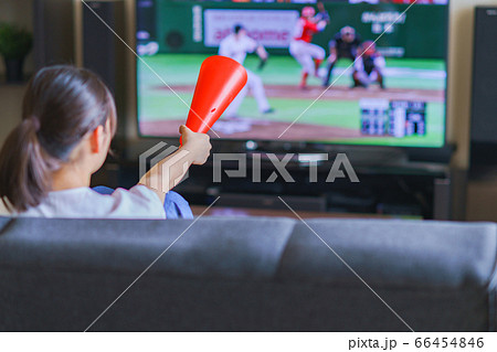 家でスポーツをテレビ観戦する若い女性のイメージ プロ野球の動画配信サービス の写真素材