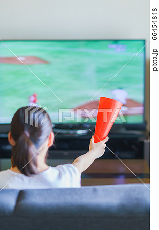 家でスポーツをテレビ観戦する若い女性のイメージ【プロ野球の動画配信サービス】 66454848