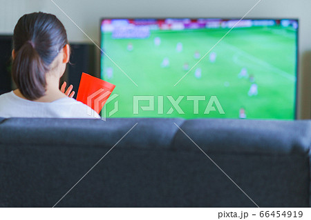 家でスポーツをテレビ観戦する若い女性のイメージ プロサッカーの動画配信サービス の写真素材