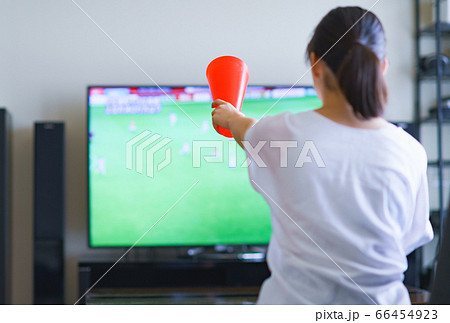 家でスポーツをテレビ観戦する若い女性のイメージ プロサッカーの動画配信サービス の写真素材