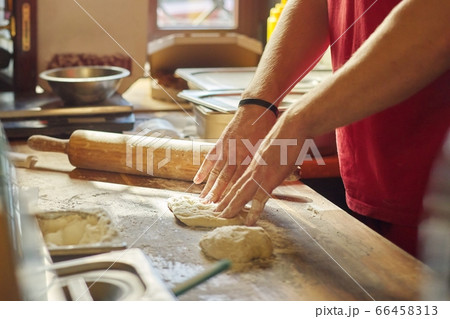 Hands of male baker with flour dough preparing food on wooden table 66458313