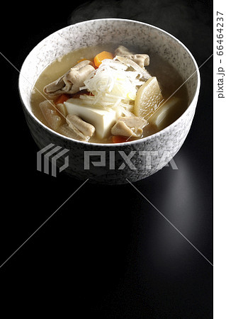 大根、人参、牛蒡、豆腐が入った具だくさんの熱々もつ煮込み（黒背景） 66464237