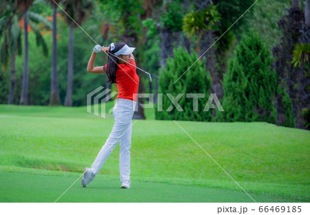 Golf player teeing off. Woman hitting golf ball from tee box with driver. Golf player teeing off. Woman hitting golf ball from tee box with driver. 66469185