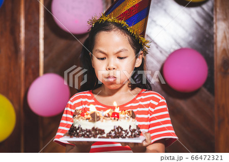 Cute asian child girl is blowing candles on delicious birthday cake in the party Cute asian child girl is blowing candles on delicious birthday cake in the party 66472321