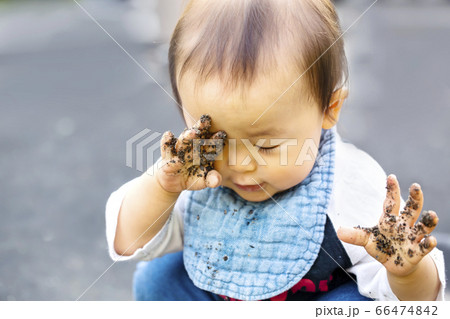 砂場で遊ぶ 砂がついている手で目をこする赤ちゃん 汚れた手で目を擦るの写真素材