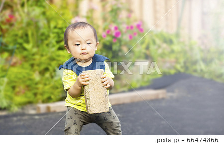 重いレンガを持って運んでいる健気でかわいい子供の姿の写真素材