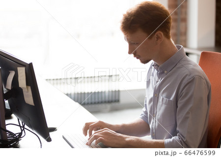 Serious businessman employee intern using computer, sitting at workplace Serious businessman employee intern using computer, sitting at workplace 66476599