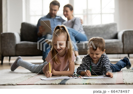 Little sister and brother playing on floor while parents relaxing 66478497